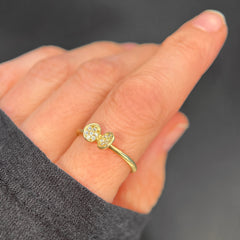 Ring with small clamshell-like object on top; each side of shell has 7 pavé diamonds; shown on index finger; in yellow gold with white diamonds