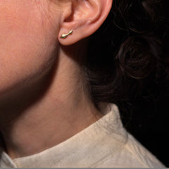 profile showing ear with one yellow gold curvy stud that looks like two connected seaweed bulbs