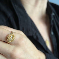 A rounded, slightly puffy shape made of ultra-lacy, modern filigree, with 5 diamonds running horizontally from one end to the other; shown worn on person wearing black shirt