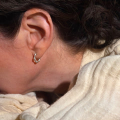 a profile photo shows a woman wearing a wavy hoop earring with tiny diamond sparkles