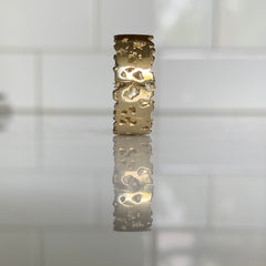 Flat band with organic holes and edges; shown in high polish; 7 mm width, 14k polished version shown standing on side 