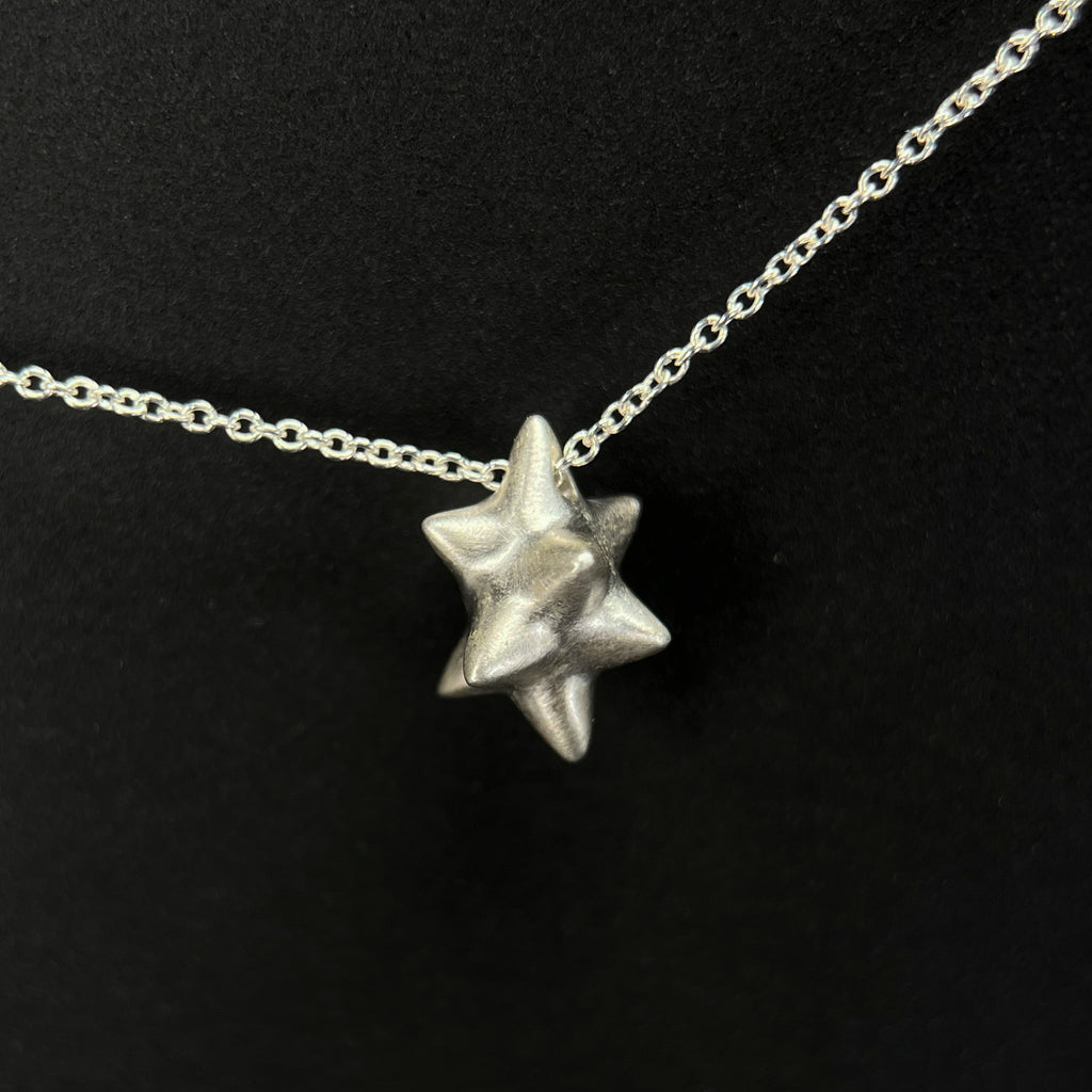 A sculptural 9 or 10 pointed asymmetrical star pendant on a thin silver chain