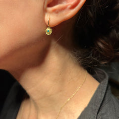 Lacy, textured, star-like earring on wire has center stone; shown here on ear with dark stone