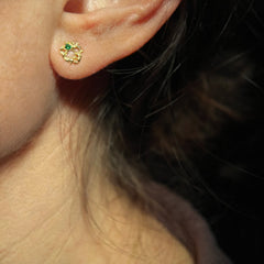 Lacy, textured, tiny stud in the shape of a irregular ring; shown with a tsavorite, on an ear
