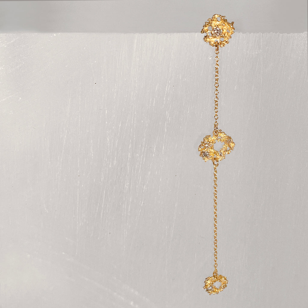 Three textured components spaced out on fine chain; top component has a post