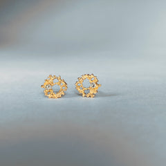 Lacy, textured, tiny stud in the shape of a irregular ring; each has a white diamond set off-center