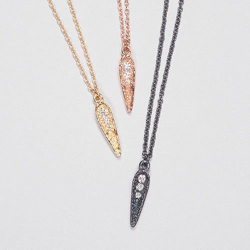 Textured, concave, spear-like shape, rounded at top and tapered at bottom, with short, vertical row of 3 consecutively smaller diamonds starting at top and ending 1/2 way down center of spear, from large to small