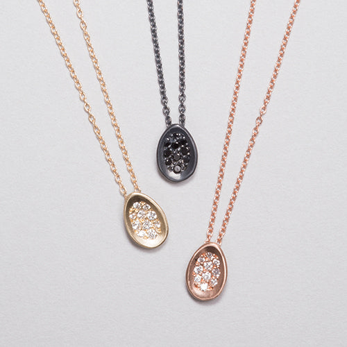 Tiny concave egg-shaped pendant with pavé diamonds; shown in 14k yellow, 14k rose, and blackened silver