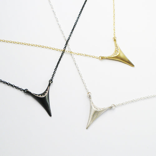 Stylized tooth with 7 diamonds in semicircle at top; connected at top corners to chain; shown in blackened silver, satin silver, and yellow gold